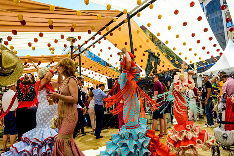 Colorfully dressed women dancing at Feria de Marbella, featured image for the article 