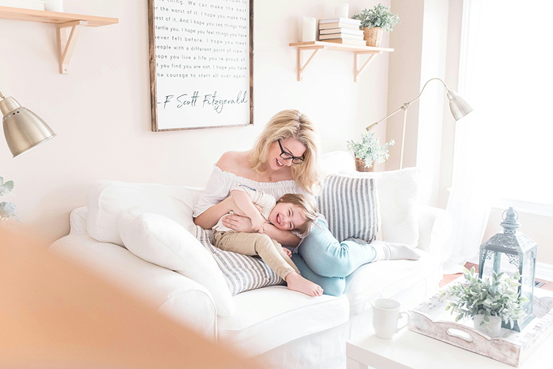 a mother and her son playfully sitting in the living room they personalized as one of the tips after buying a house